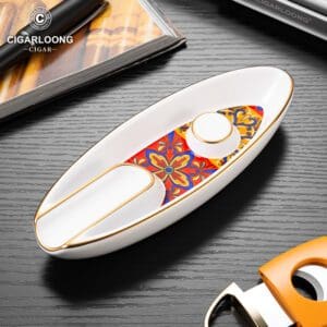 White ceramic boat-shaped ashtray with a colorful floral inlay and gold trim, brand logo visible in the corner.